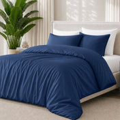 Dark blue bedding set on a bed with a plant in the background
