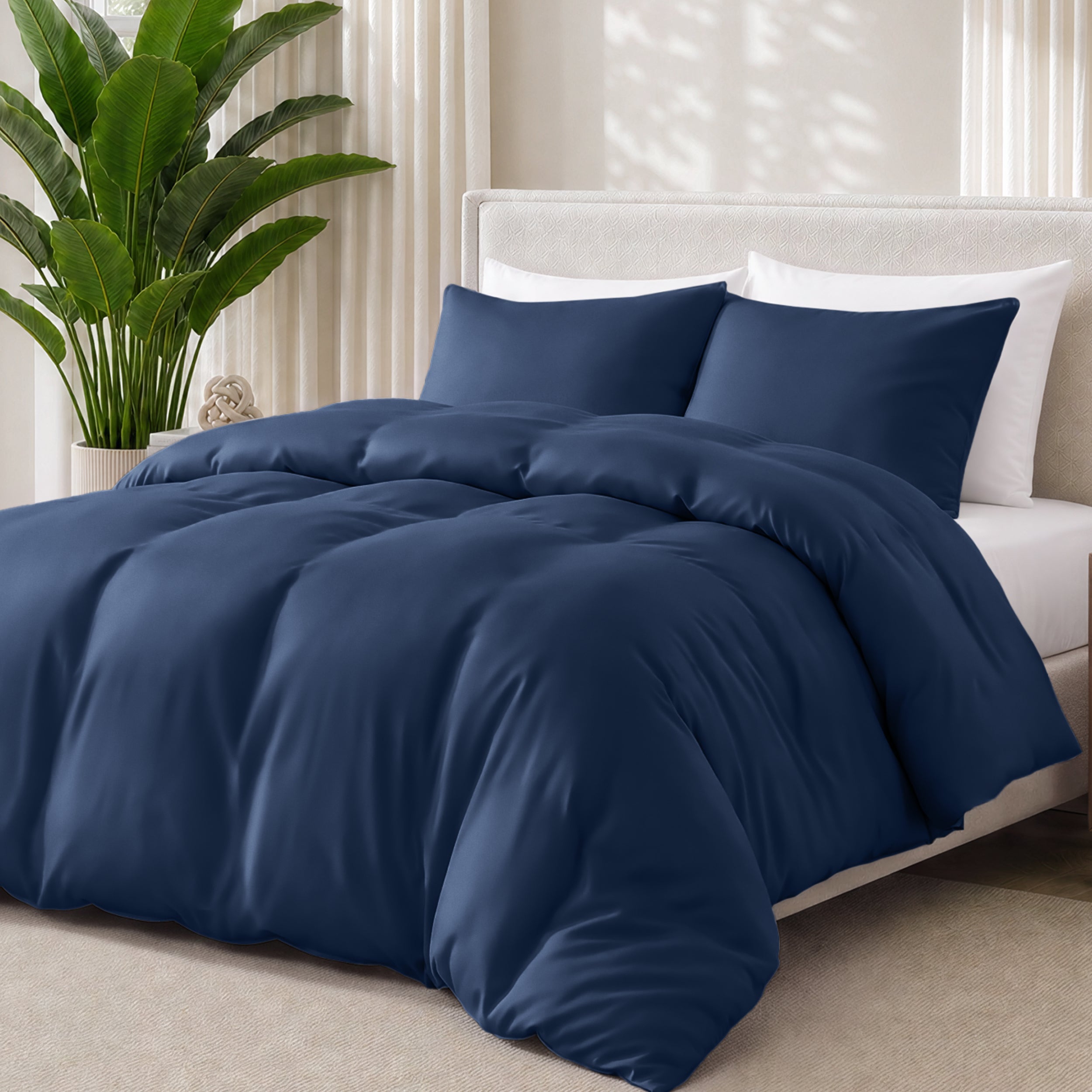Dark blue bedding set on a bed with a plant in the background