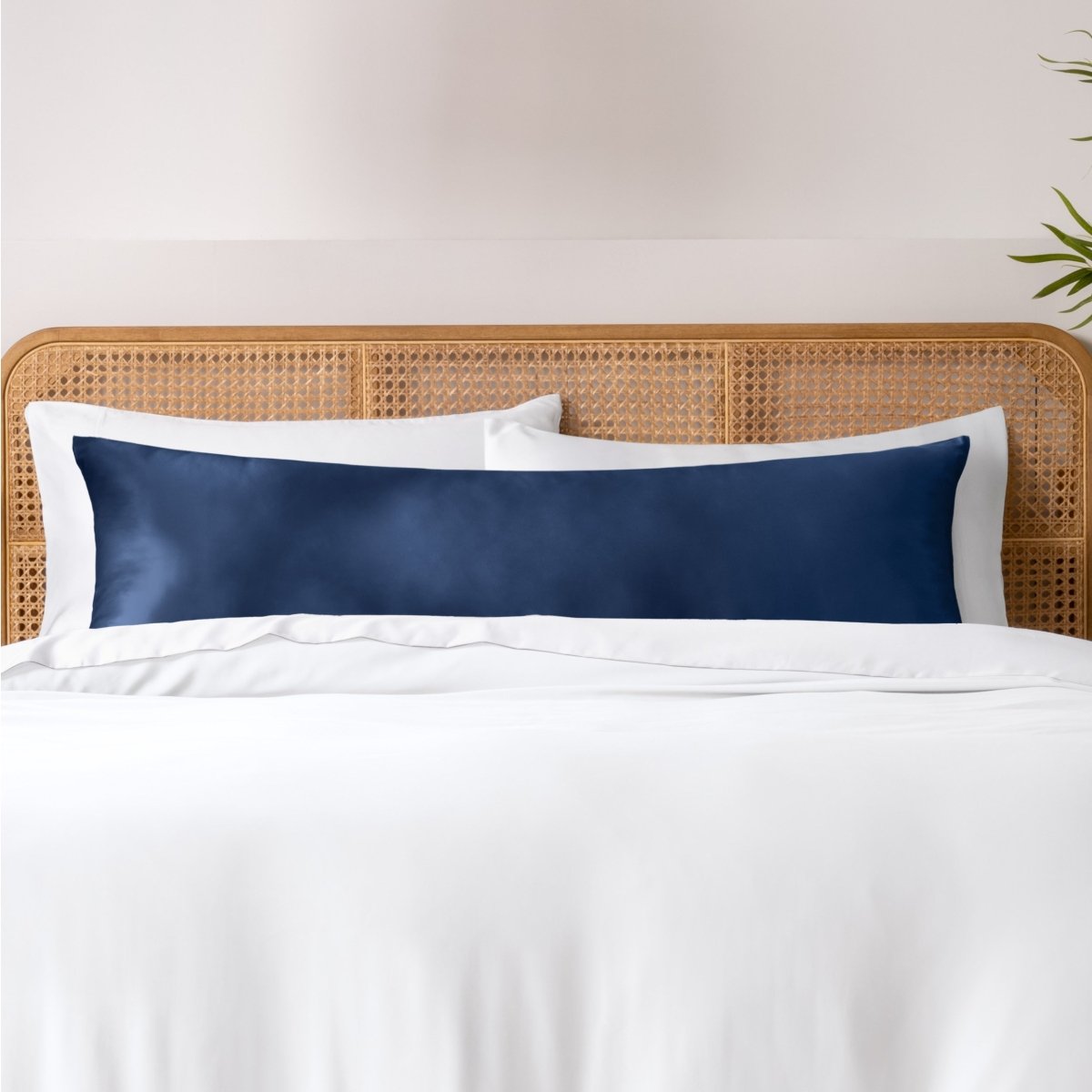 Pillows, sheets and a duvet cover on a bed with a wicker headboard and light gray bedding.