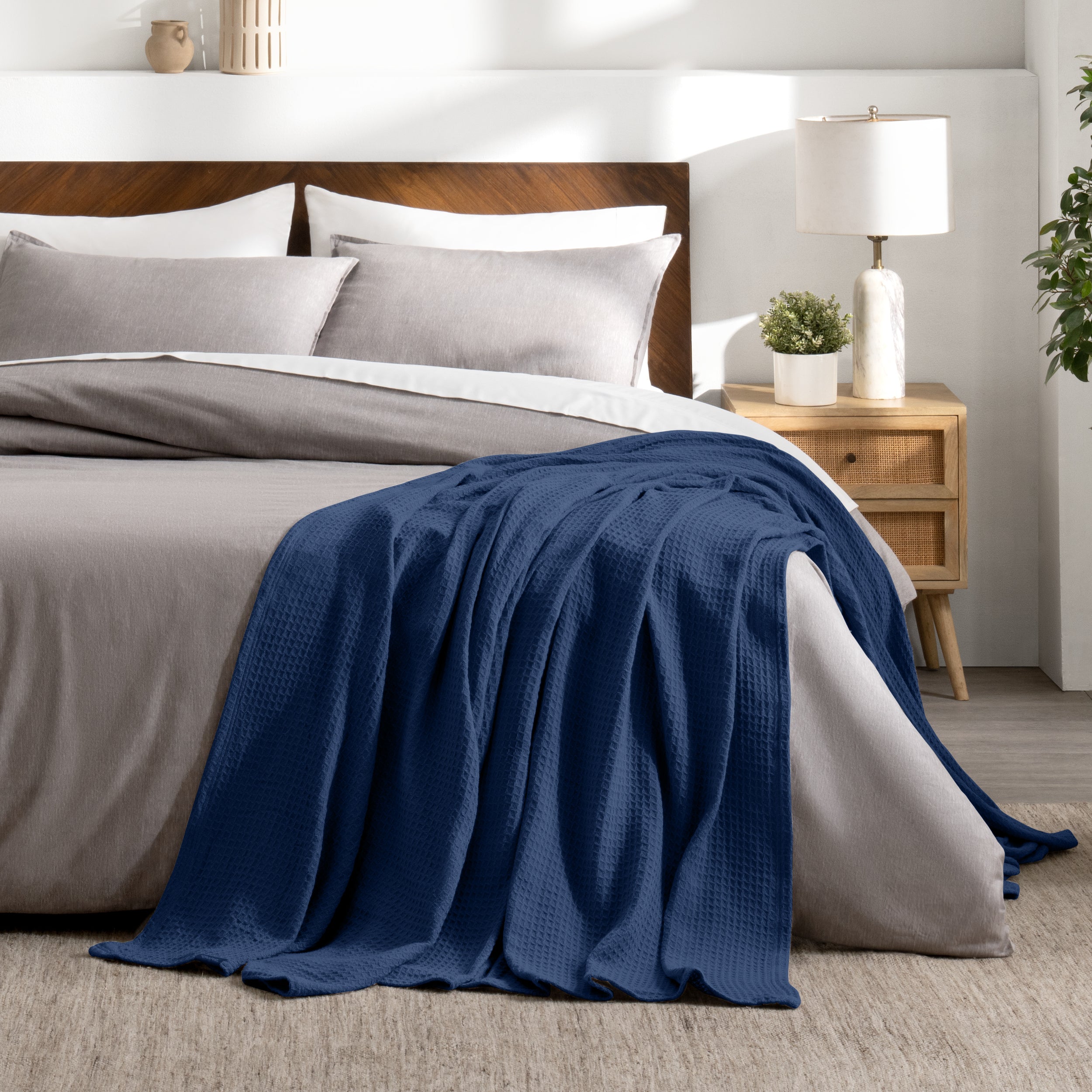Bed with gray bedding and a throw blanket in a bedroom setting.