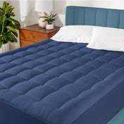 A cotton top mattress pad on a mattress in a modern bedroom.