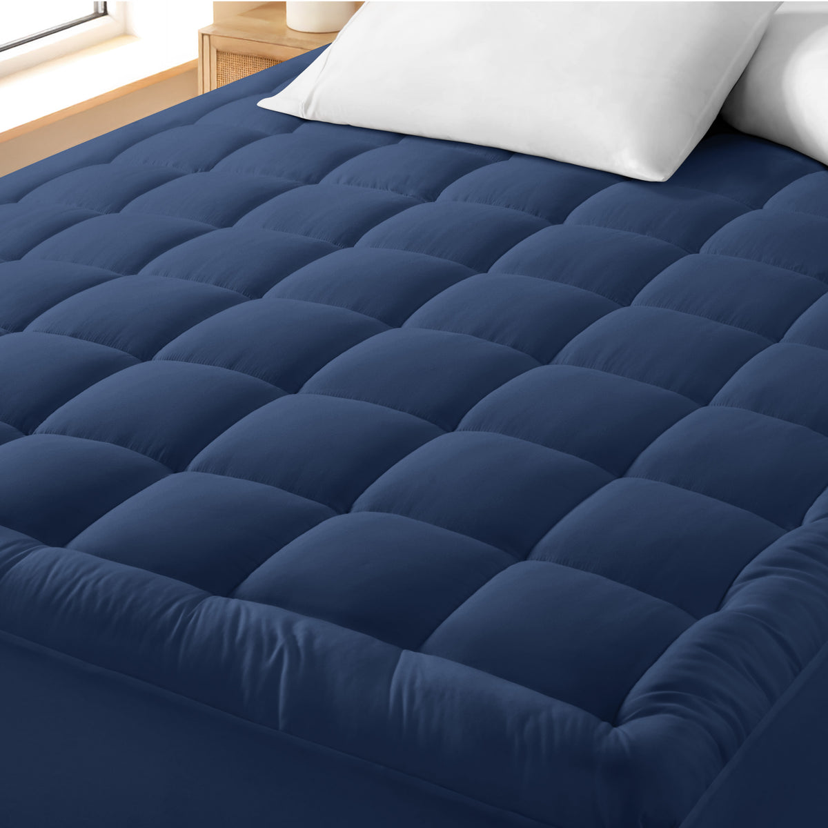 A cotton top mattress pad on a mattress in a modern bedroom.