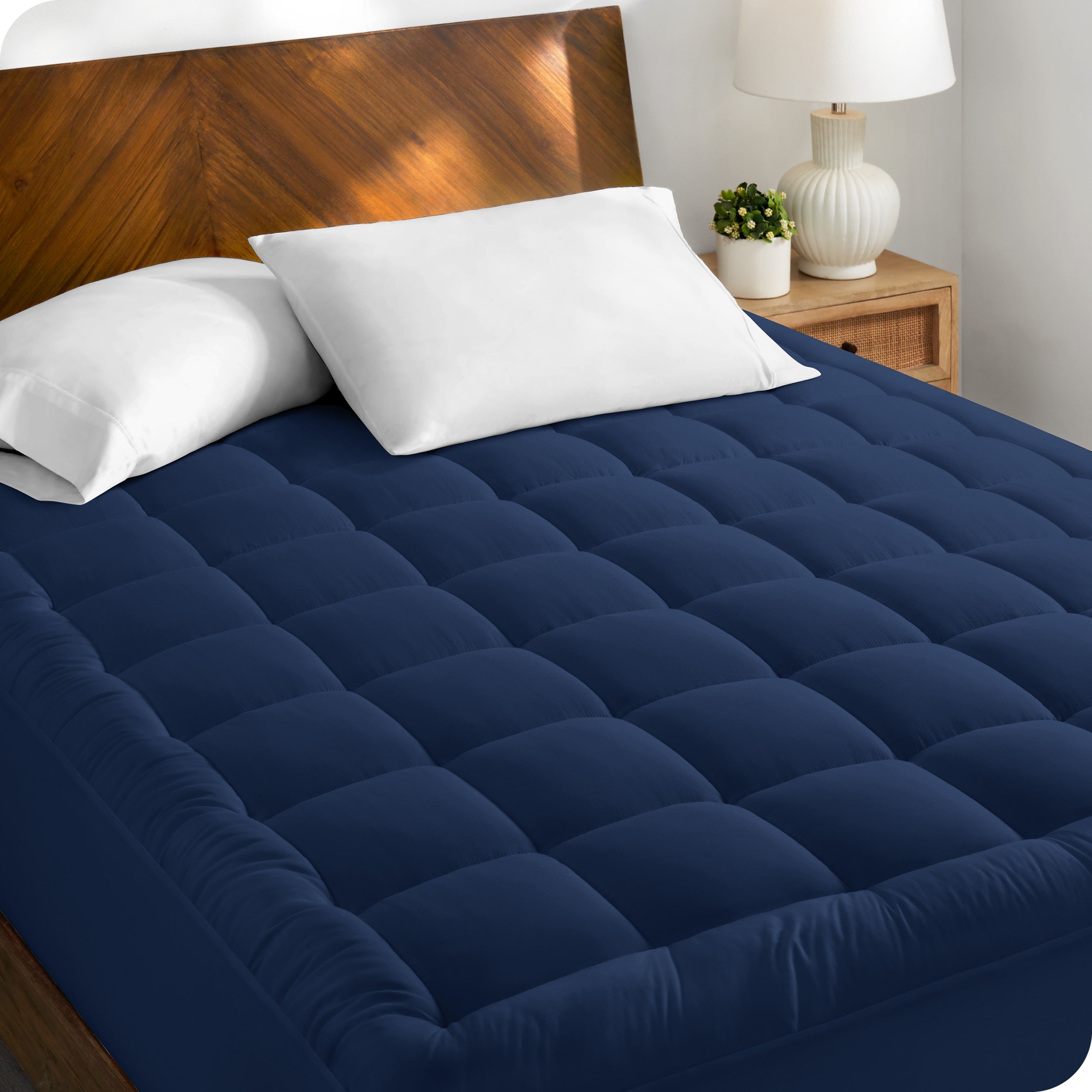 A cotton top mattress pad on a mattress in a modern bedroom.