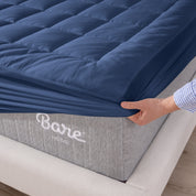 A corner of a mattress on a wood frame. A mattress pad is covering the mattress.