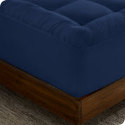 A corner of a mattress on a wood frame. A mattress pad is covering the mattress.