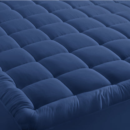 A mattress pad on a bed with 2 pillows on top