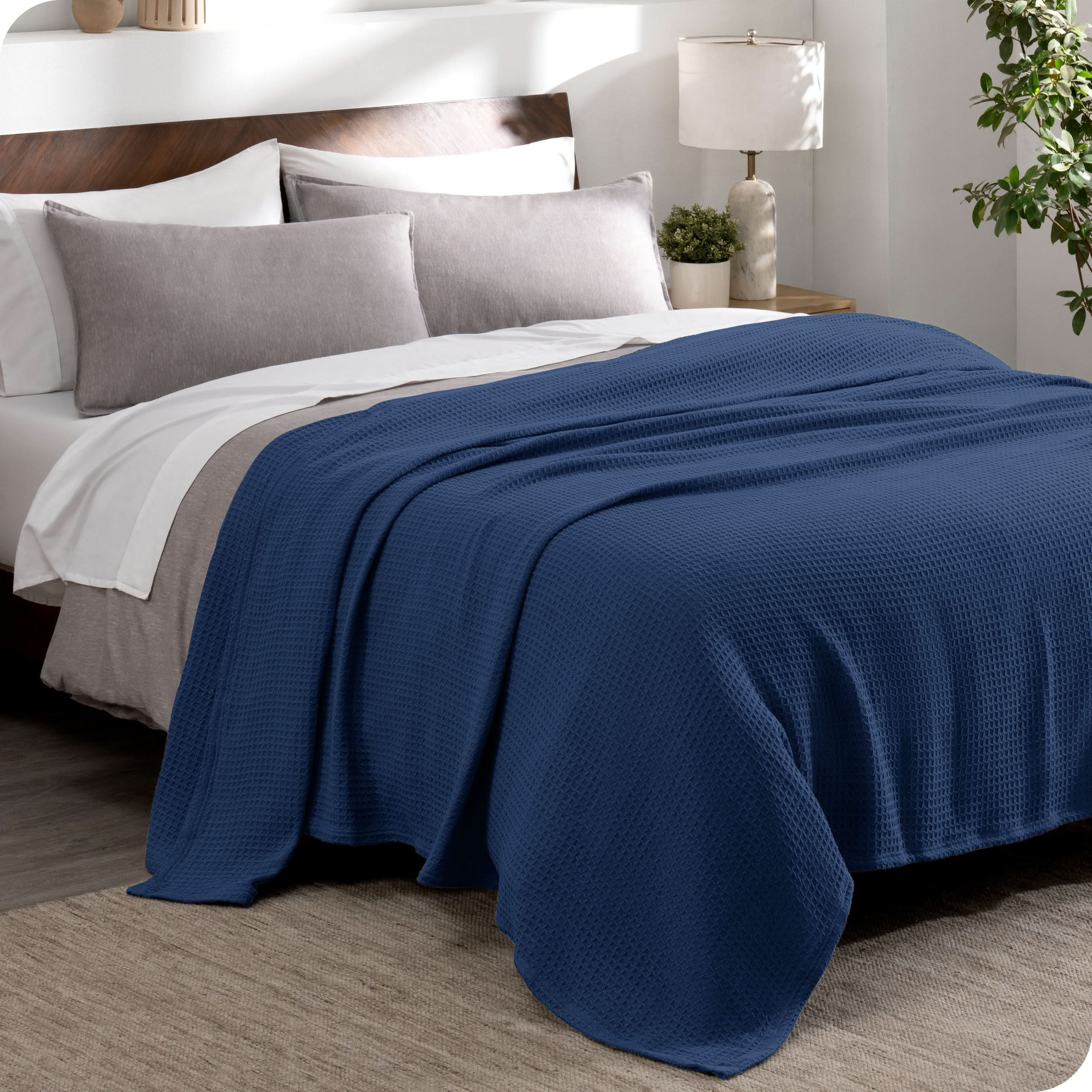 A cotton waffle blanket draped over the top of a bed made with a duvet set