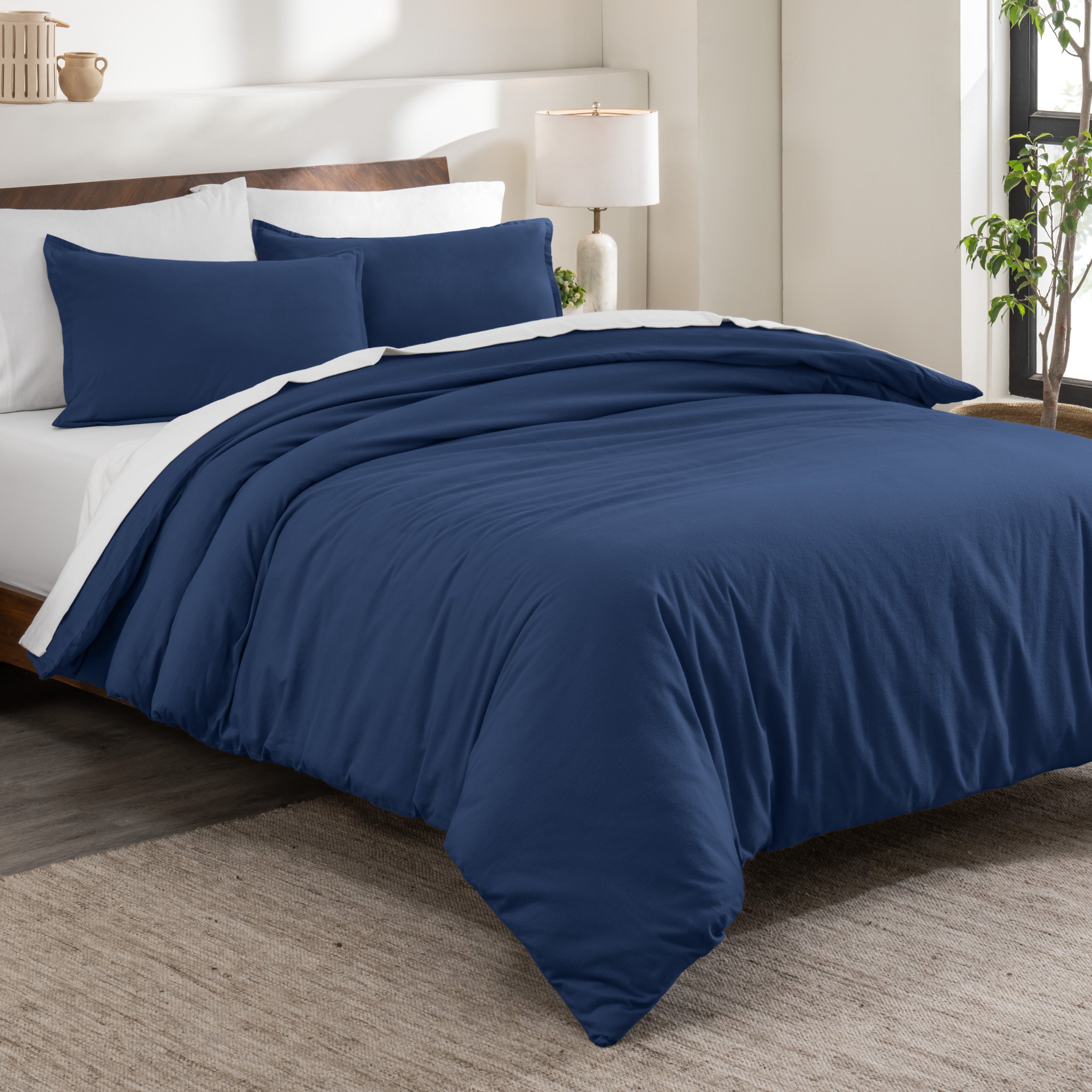 Flannel duvet cover set on a bed in a bedroom with a lamp and plant in the background.