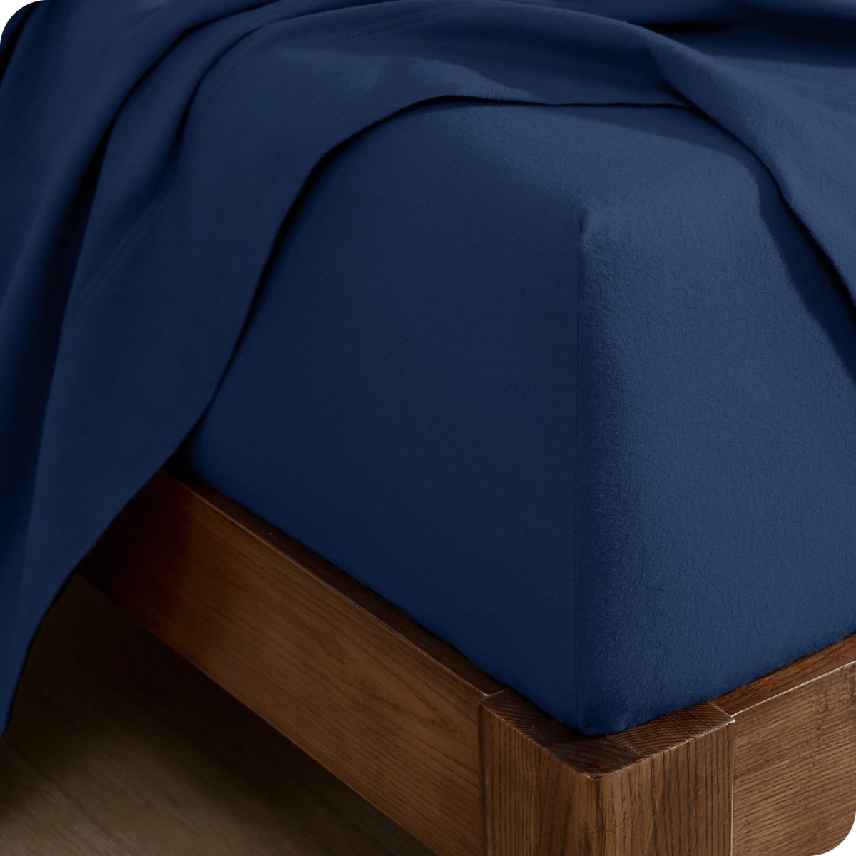 Corner of a bed with a flannel fitted sheet and top sheet on it