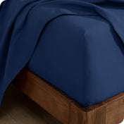 Corner of a bed with a flannel fitted sheet and top sheet on it