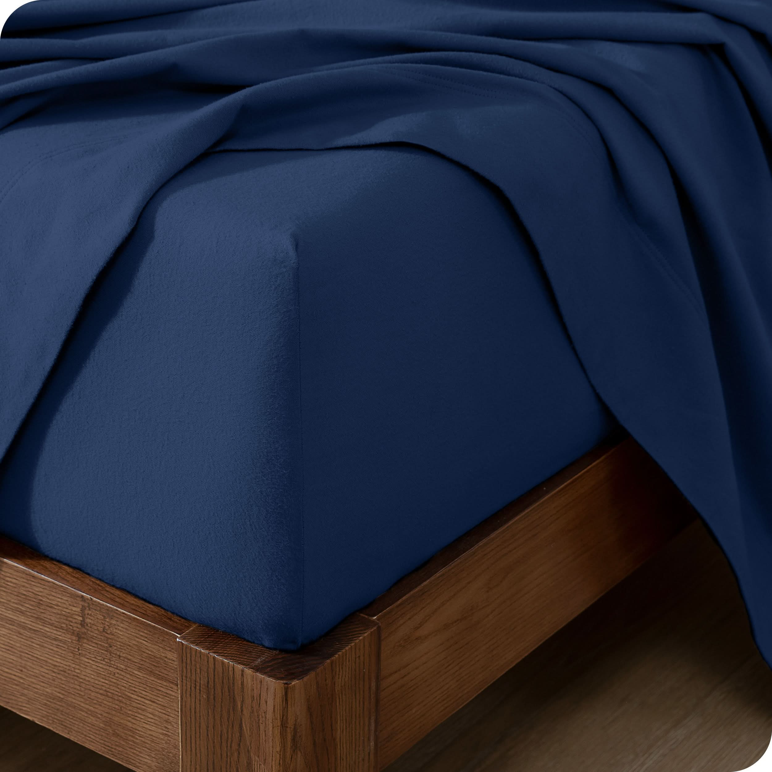 Close up of the corner of a mattress with a flannel fitted sheet and flat sheet on it