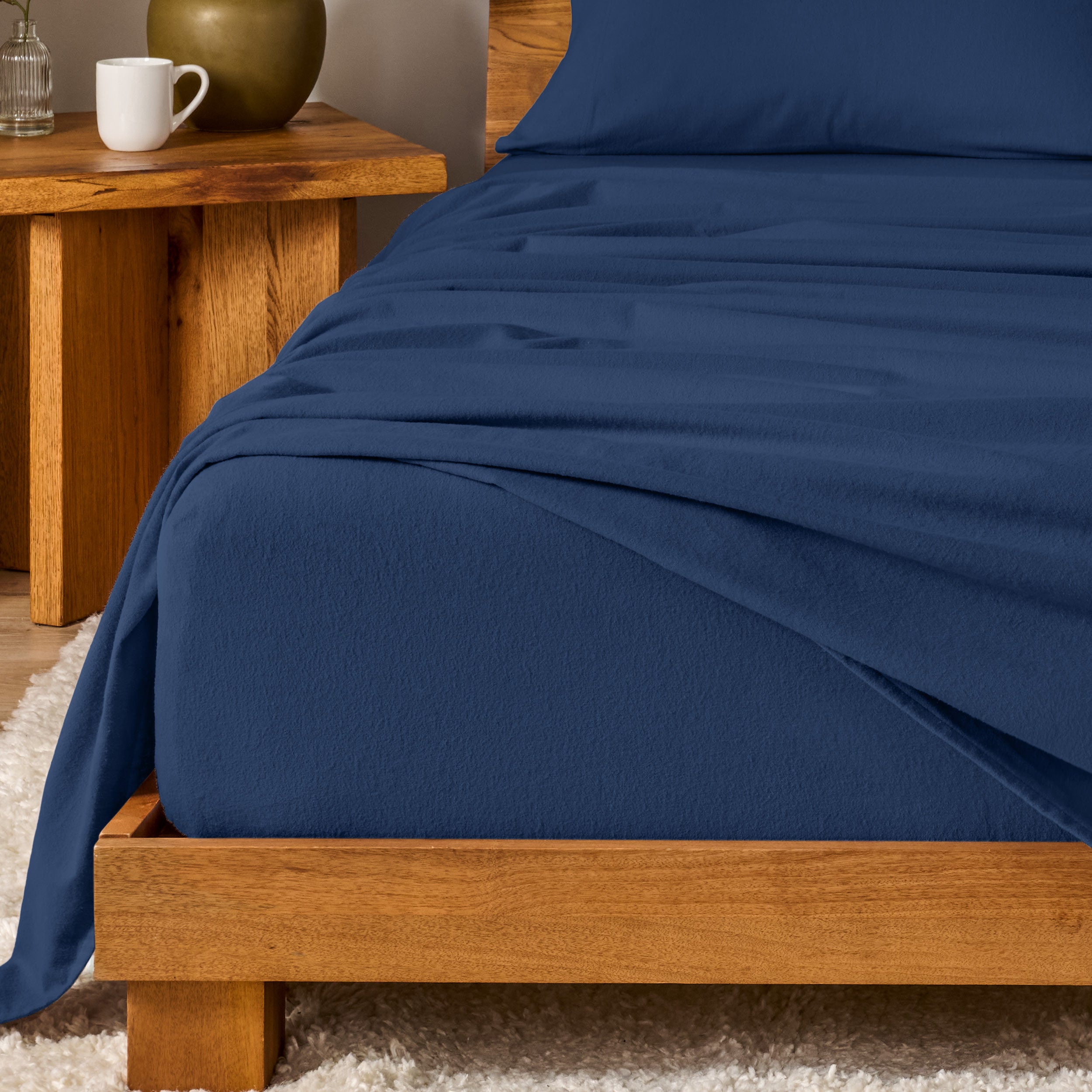 Bed with flannel bedding and wooden headboard and nightstand next to it.