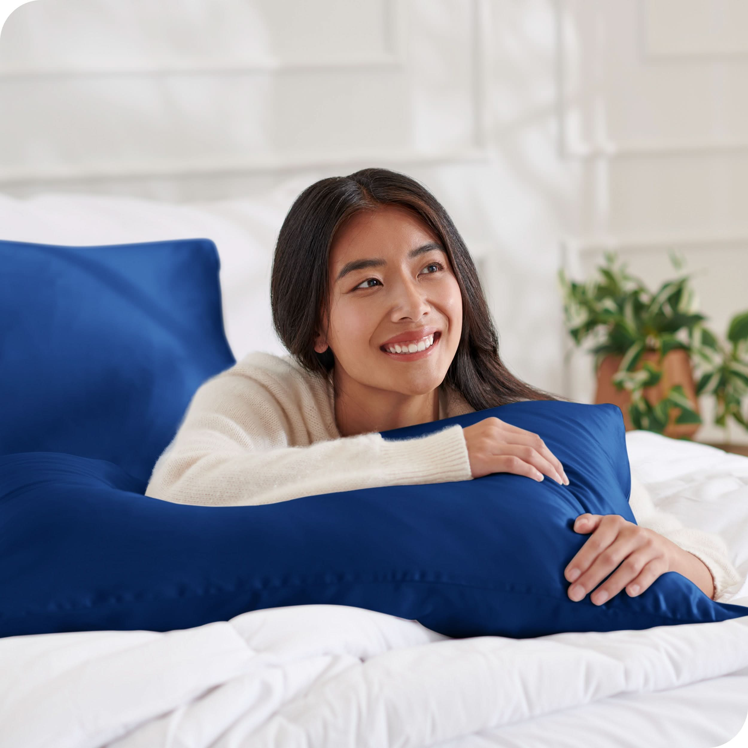 A woman on a bed with a silk pillowcase covered pillow