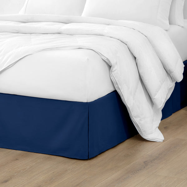 A modern bed with a microfiber bed skirt with pleats on the corners and midway on each side