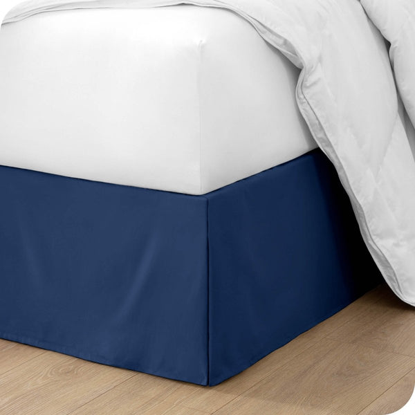 The corner of a bed with a bed skirt and comforter on it