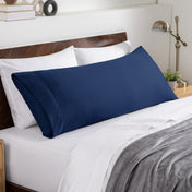 Bed sheets and pillows on a neatly made bed with a wooden headboard.