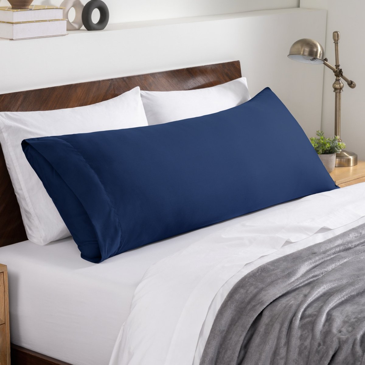 Bed sheets and pillows on a neatly made bed with a wooden headboard.
