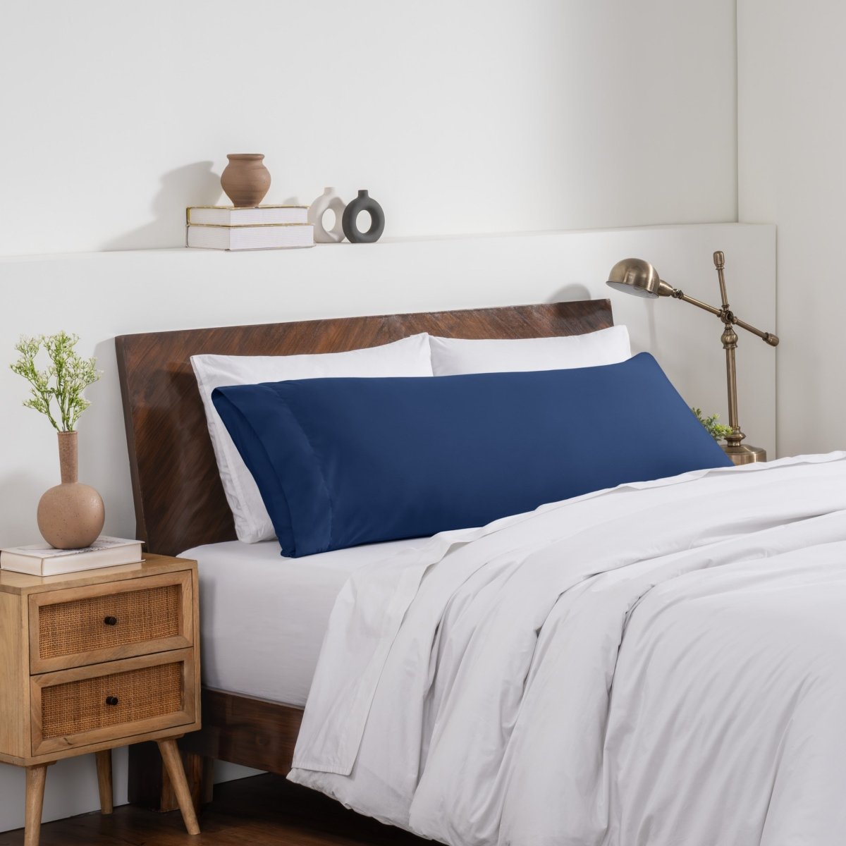 Bedroom with a wooden headboard and white bedding, featuring a nightstand and decorative items.
