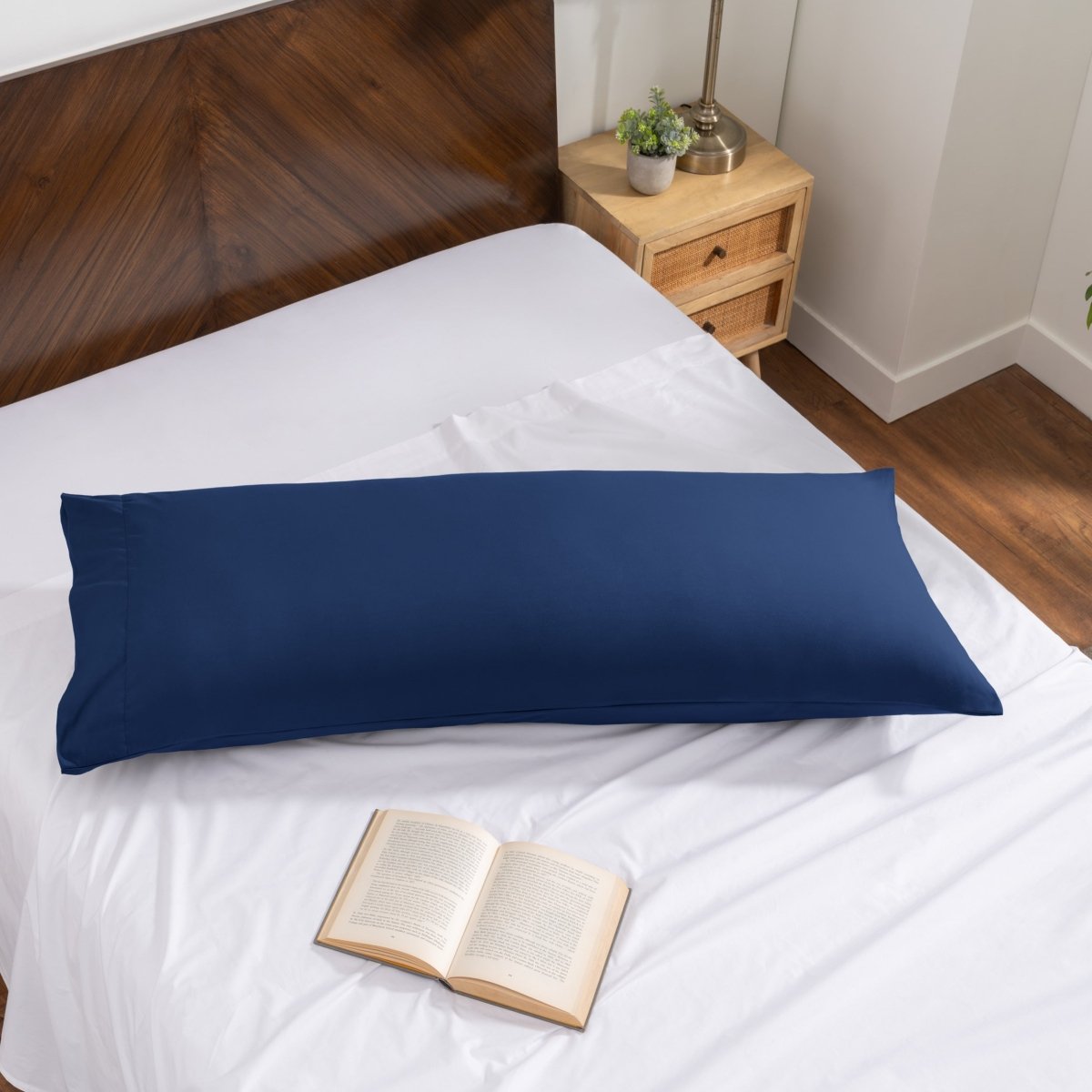 Pillowcase on a body pillow with a wooden headboard and plant in the background