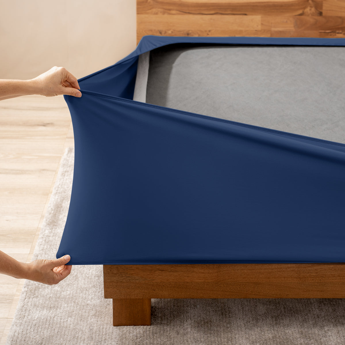 A person stretching a box spring cover
