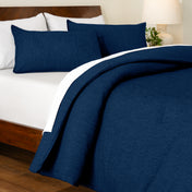 Track stitch comforter on a bed with white pillows and a wooden headboard.