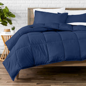 Comforter set on a bed with a white brick wall and plant in the background