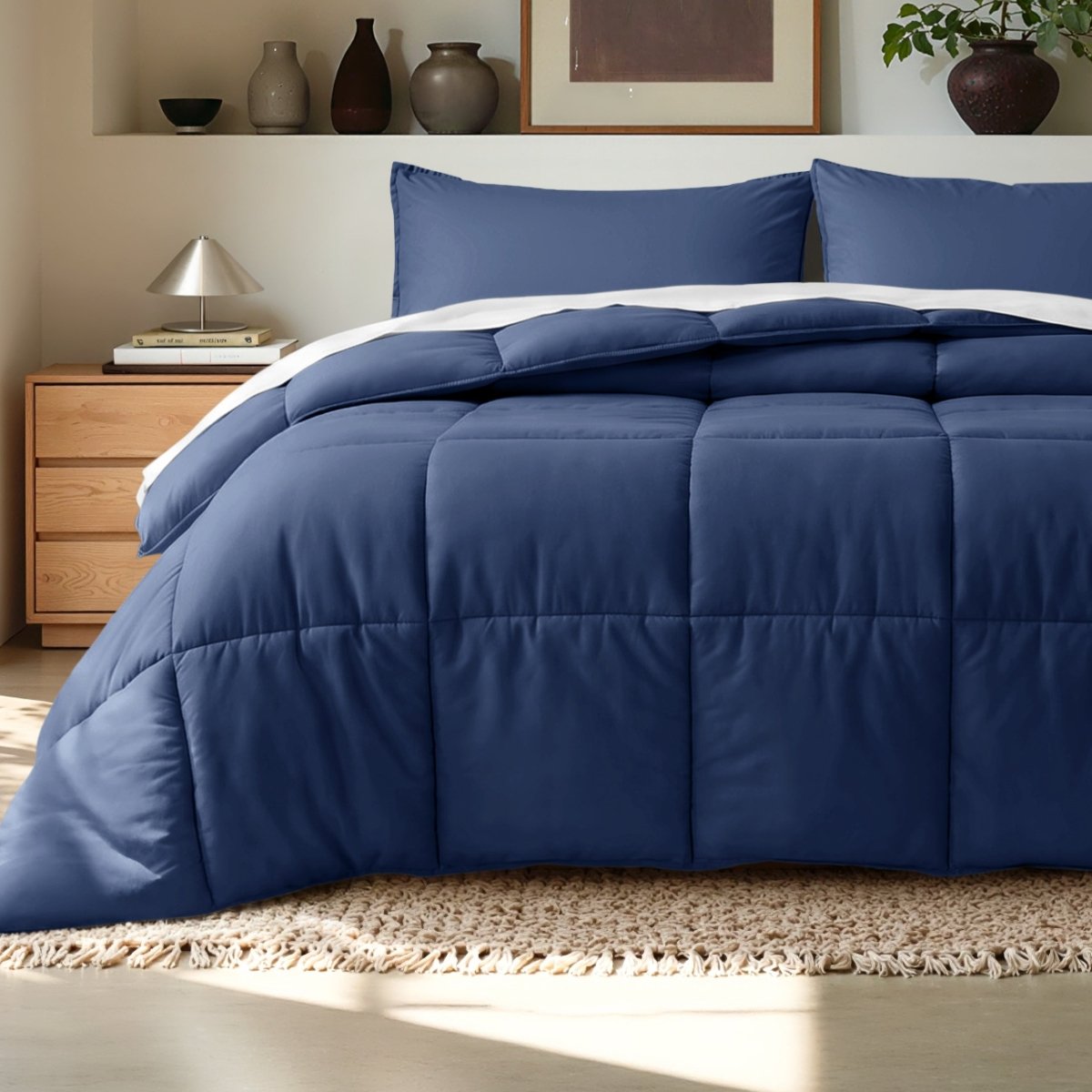 Comforter on a bed in a bedroom setting with a wooden nightstand and decorative items.