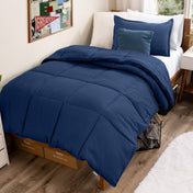 Bed with comforter and pillows in a dorm room