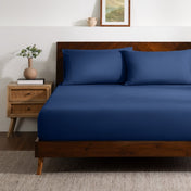 A bed made with a single fitted sheet and two matching pillowcases.