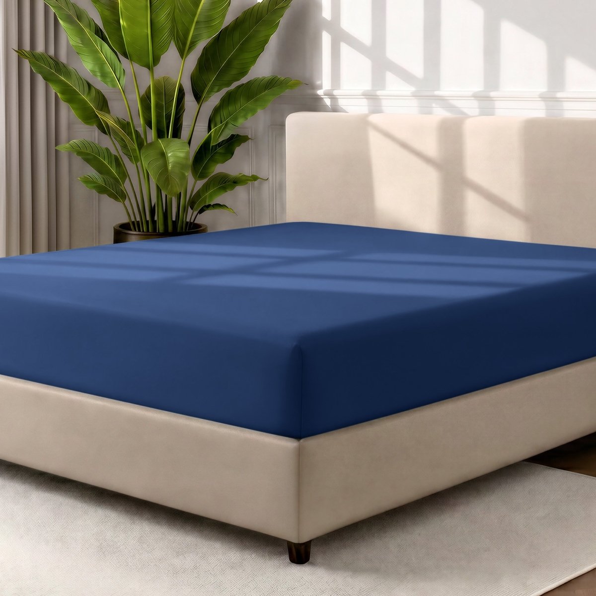 A fitted sheet covering a bed with a cream colored frame, styled in a bedroom setting with a large potted plant.