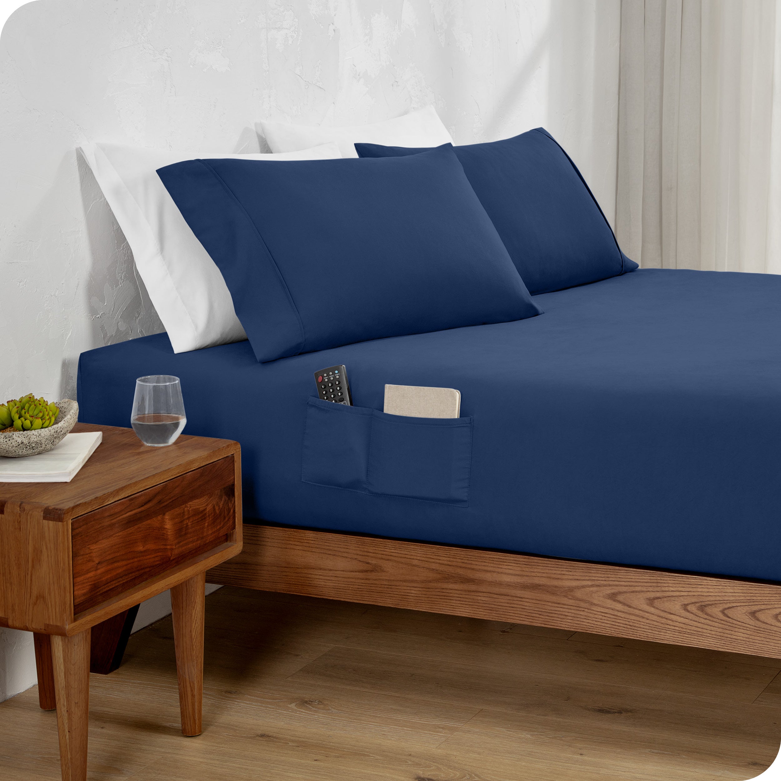 Bed made with a blue fitted sheet which has pockets on the side