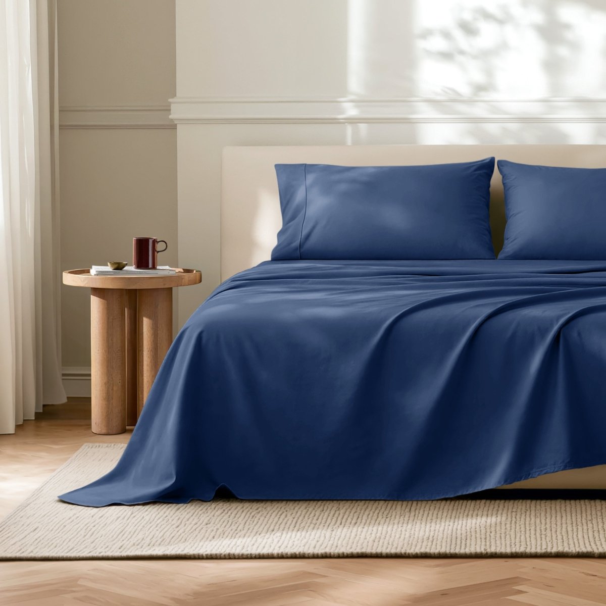 Microfiber flat sheet on a bed in a bedroom with a wooden side table.