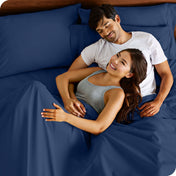 A couple is relaxing in bed with pillows behind them