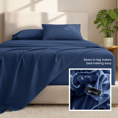 Bed sheets and pillows on a bed with a plant in the background