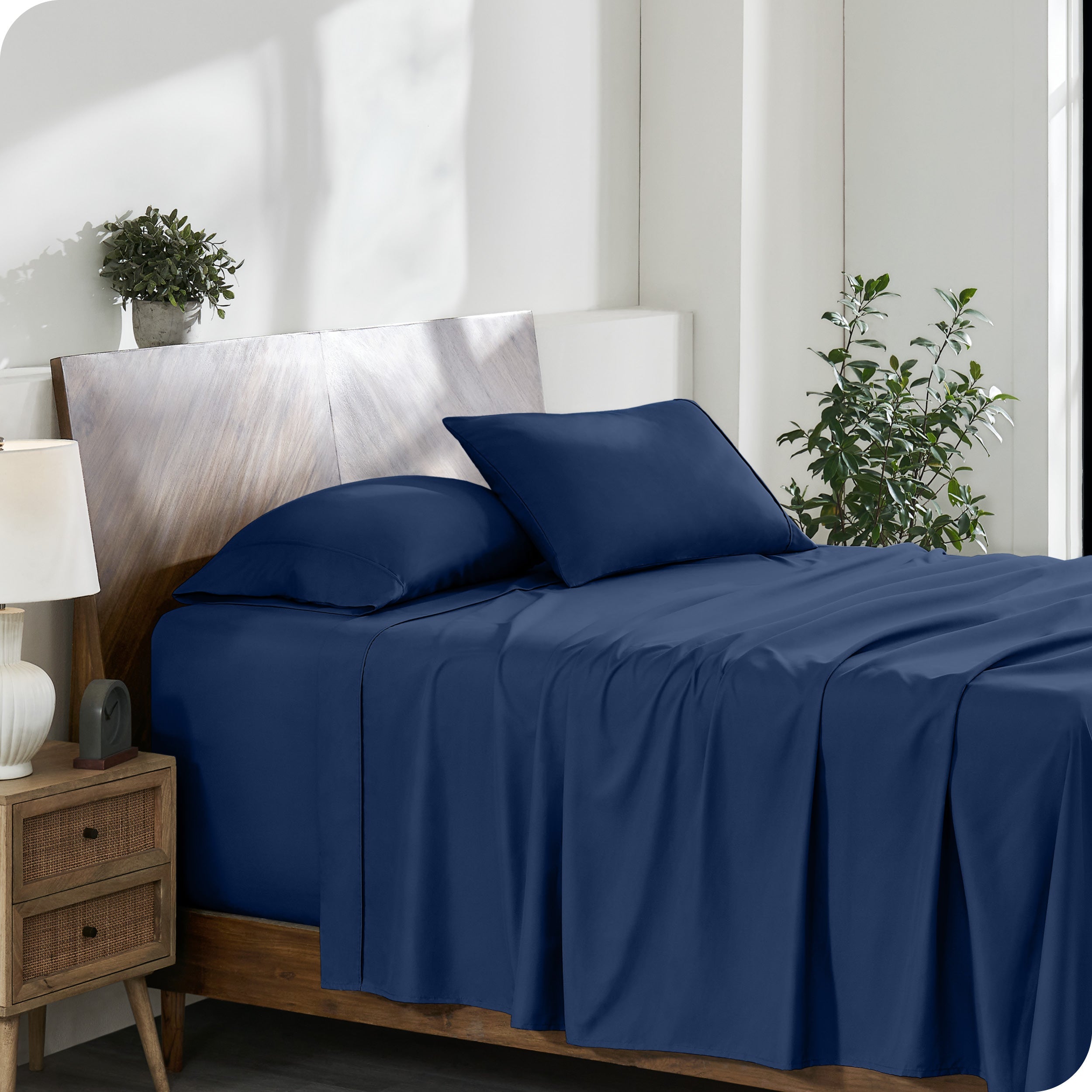 A side view of a modern bed with a microfiber sheet set on it.