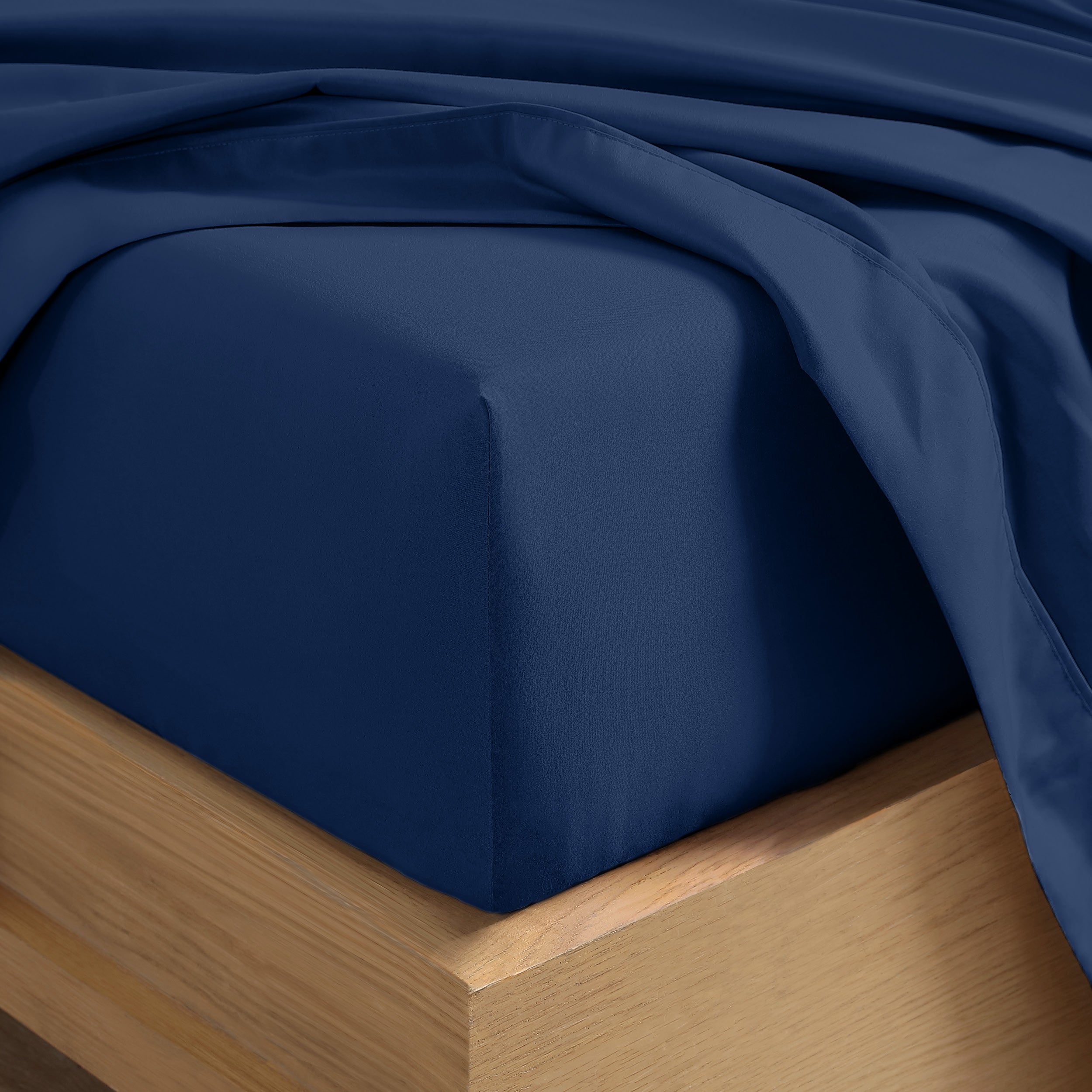 Close up of the corner of a mattress with a fitted sheet and flat sheet on it