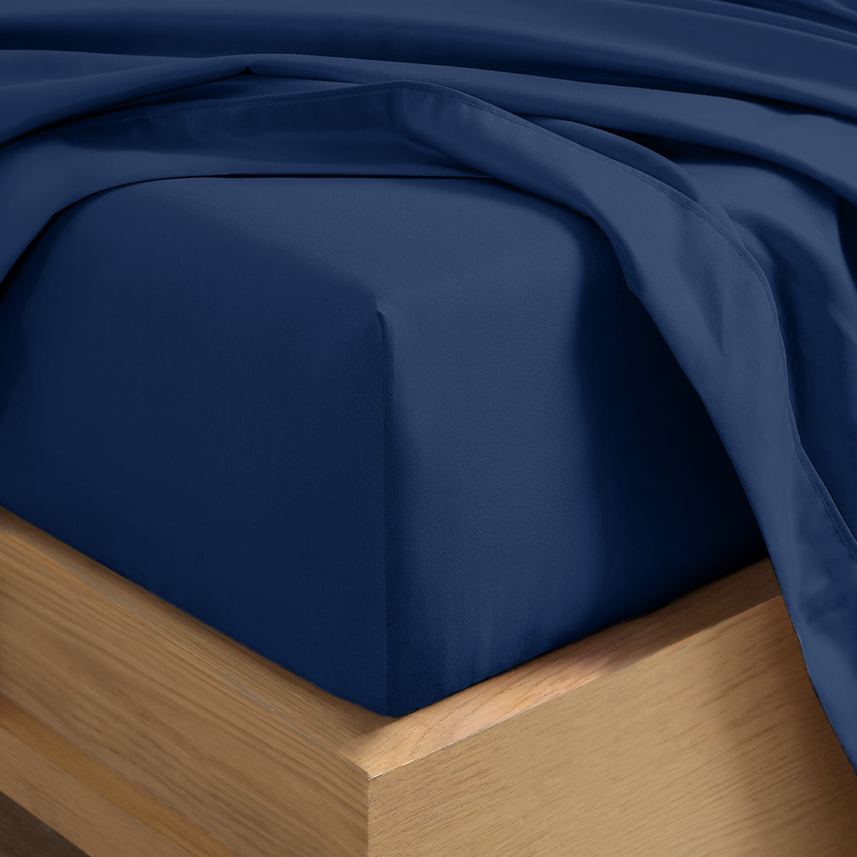 Close up of the corner of a mattress with a fitted sheet and flat sheet on it