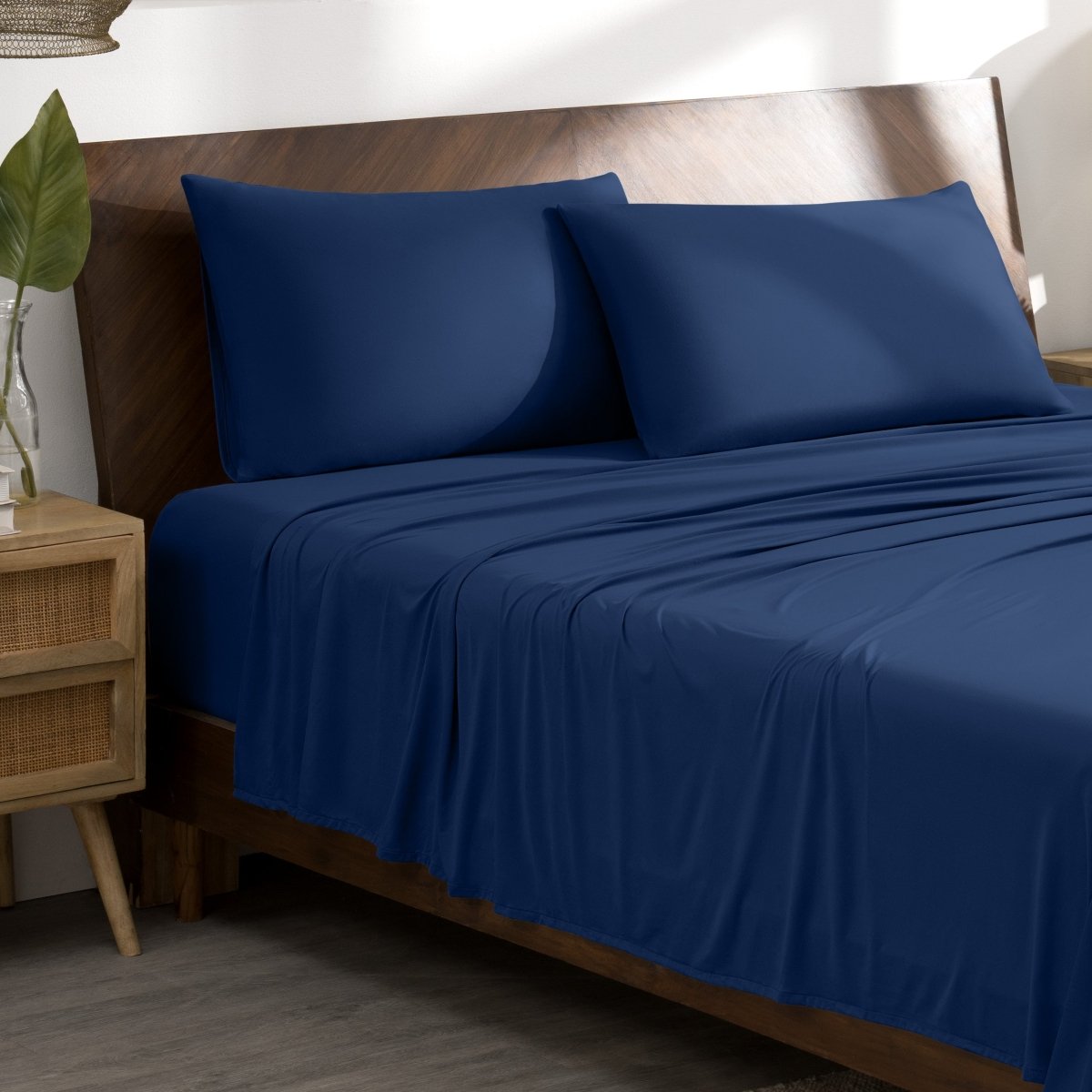 Microfiber stretch bed sheets and pillows on a wooden bed in a bedroom setting.