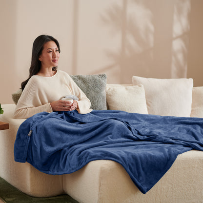 A woman sitting on a couch with a microplush blanket on her lap
