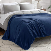 A textured microplush blanket is covering a bed, which has a comforter set on it.