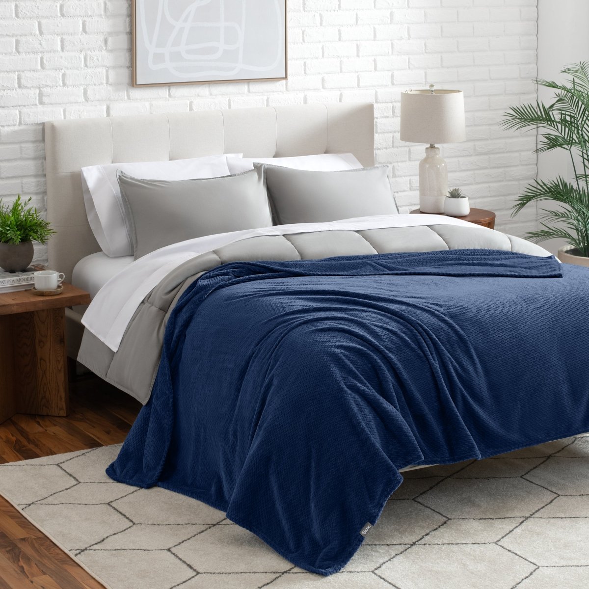 Neatly made bed with a blanket draped over the end of the bed