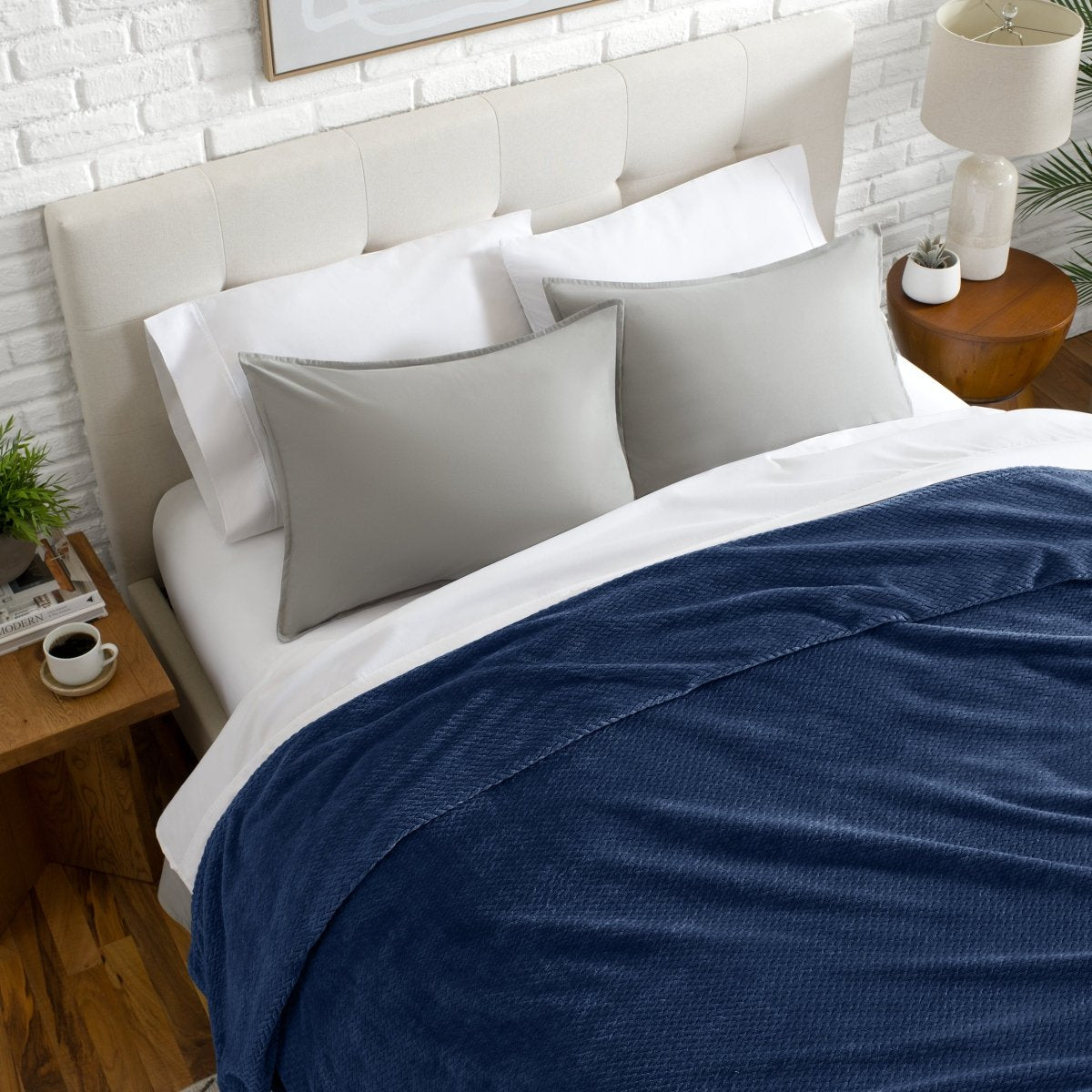 Neatly made bed with a chevron blanket over the comforter