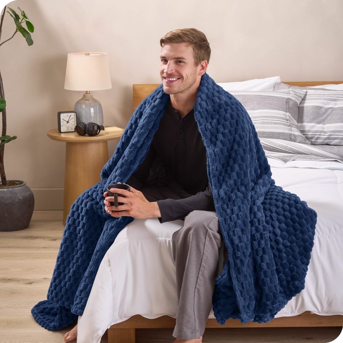 A man sitting on a bed wrapped in a microplush blanket