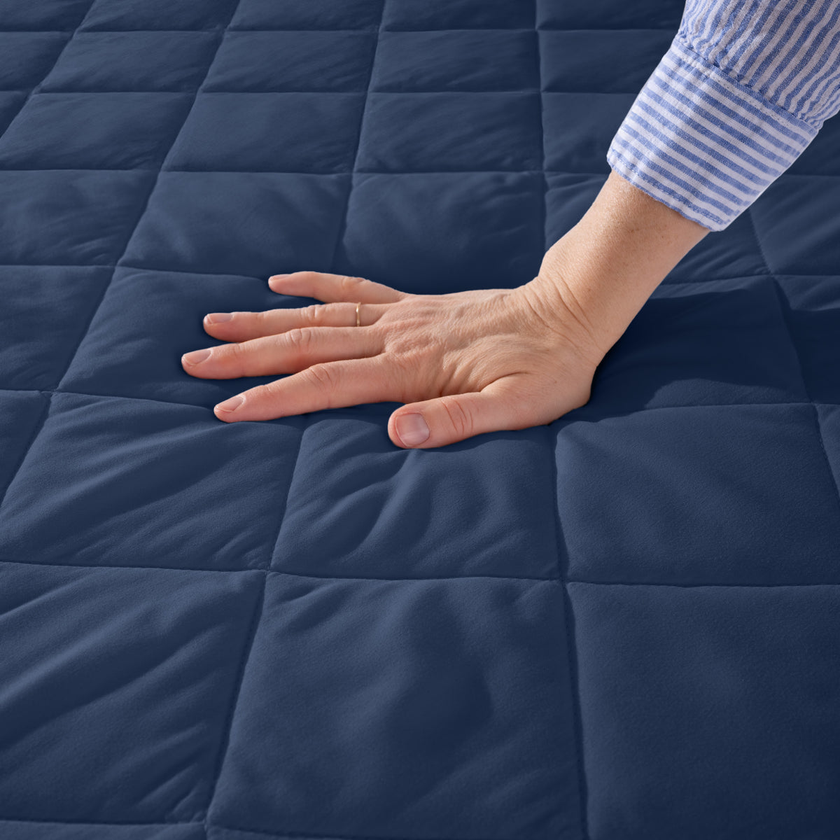Hand touching a quilted mattress pad.