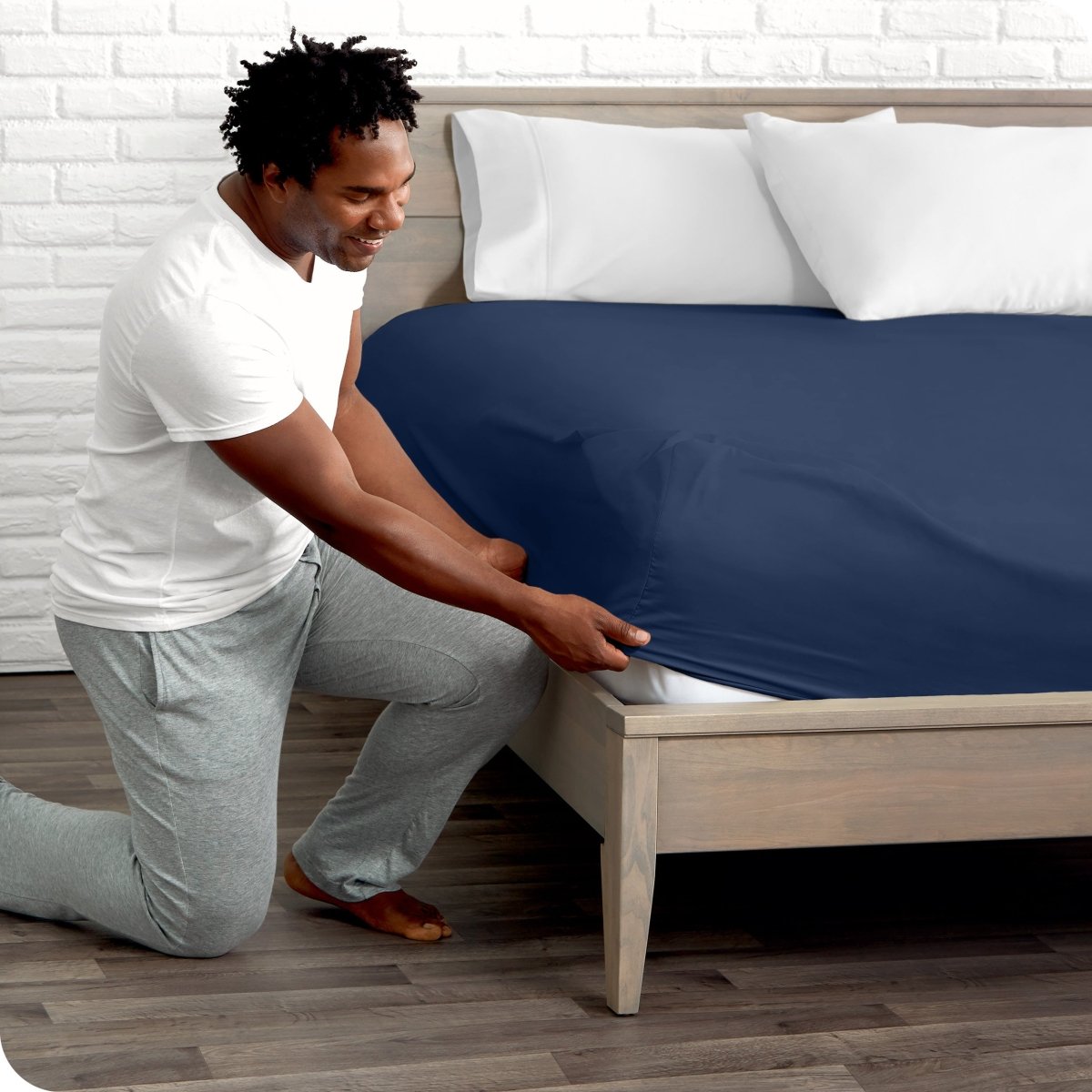 Man putting the corner of fitted sheet on a mattress