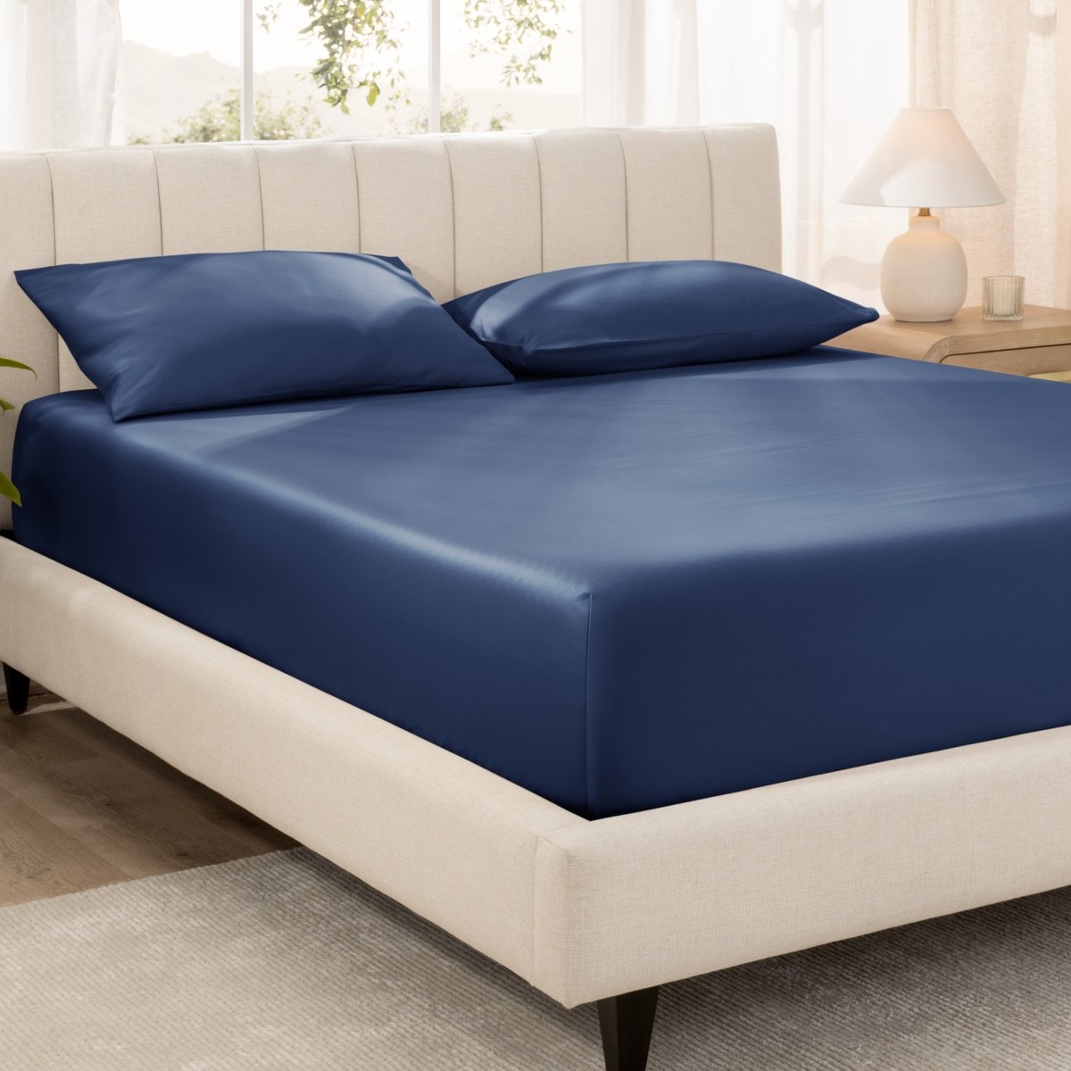 Bed with fitted sheet and pillowcases in a bright room.