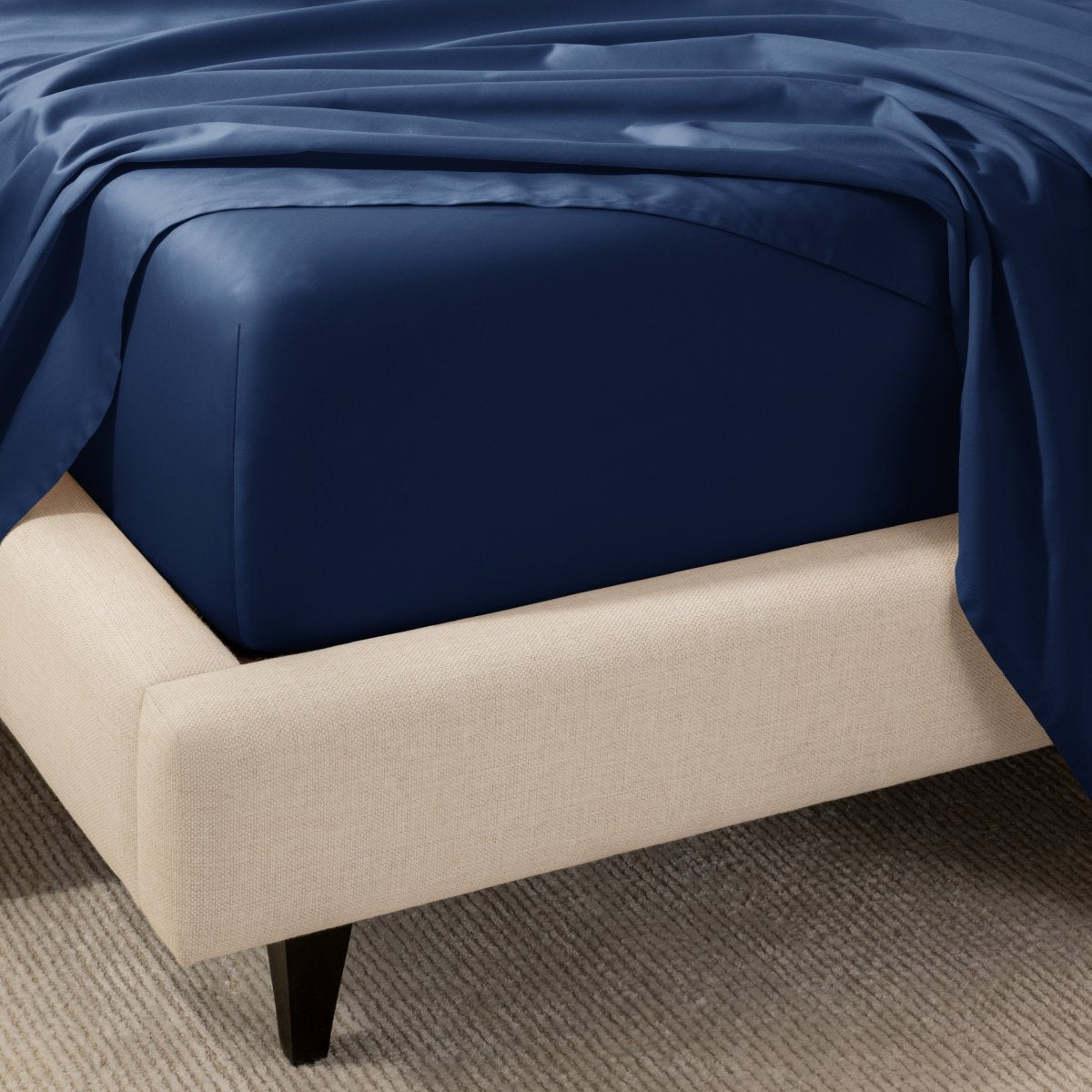 A close-up of the corner of a bed with a fitted sheet and matching flat sheet.