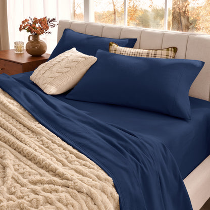 Neatly made bed with organic flannel sheets  and a beige blanket in a bright bedroom.