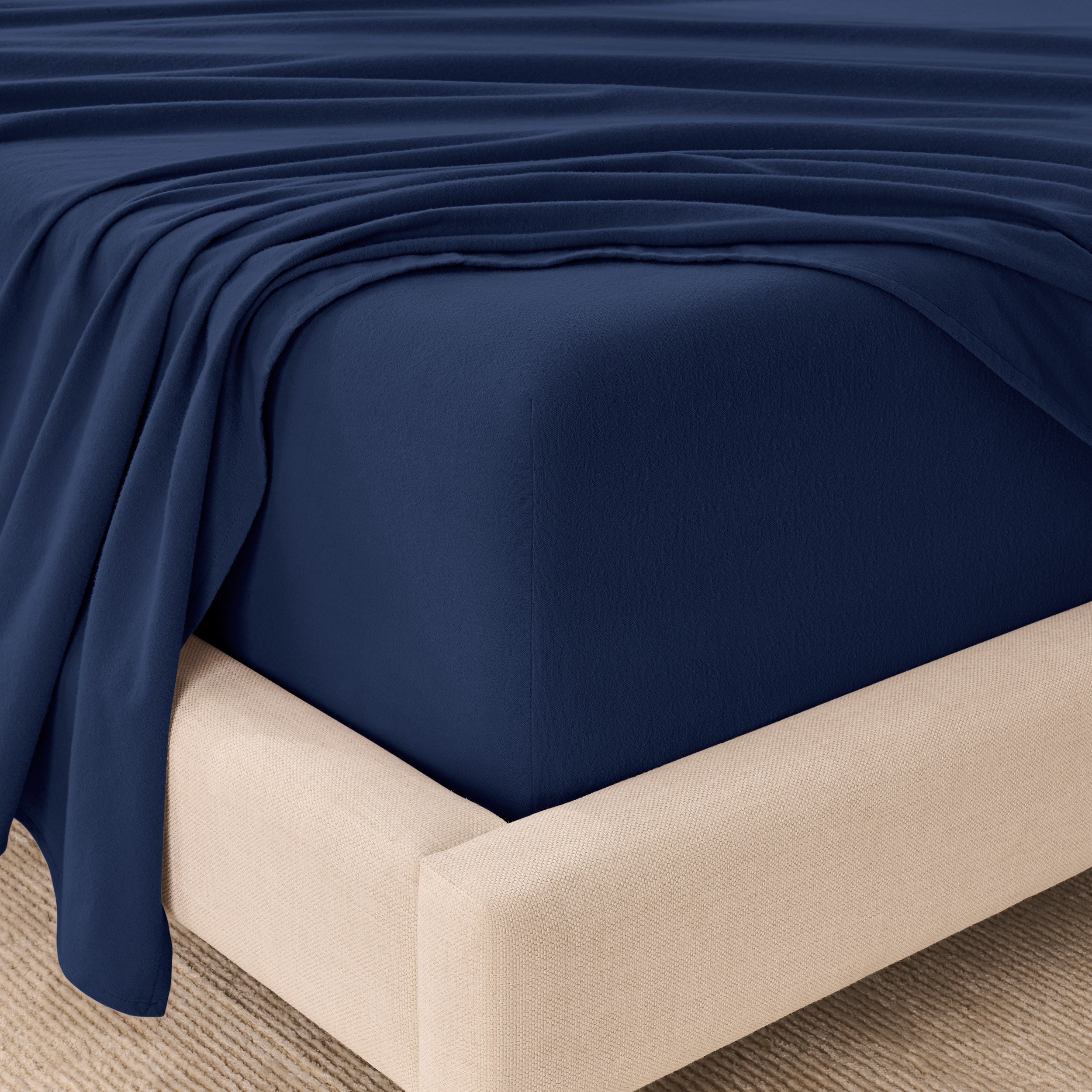 Fitted sheet and top sheet on a mattress with a beige bed frame