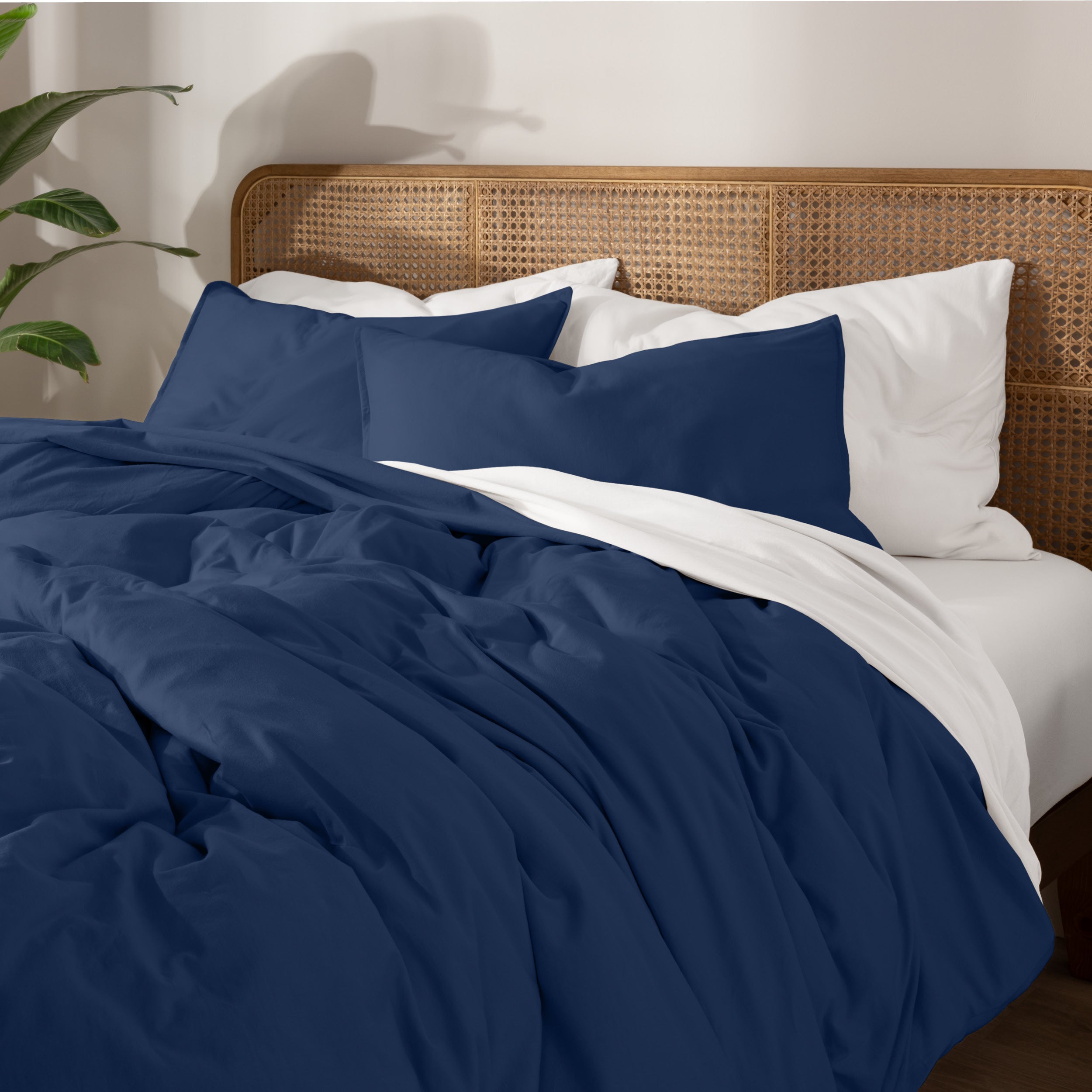 Bedding set on a bed with a wicker nightstand and lamp in a bedroom setting.